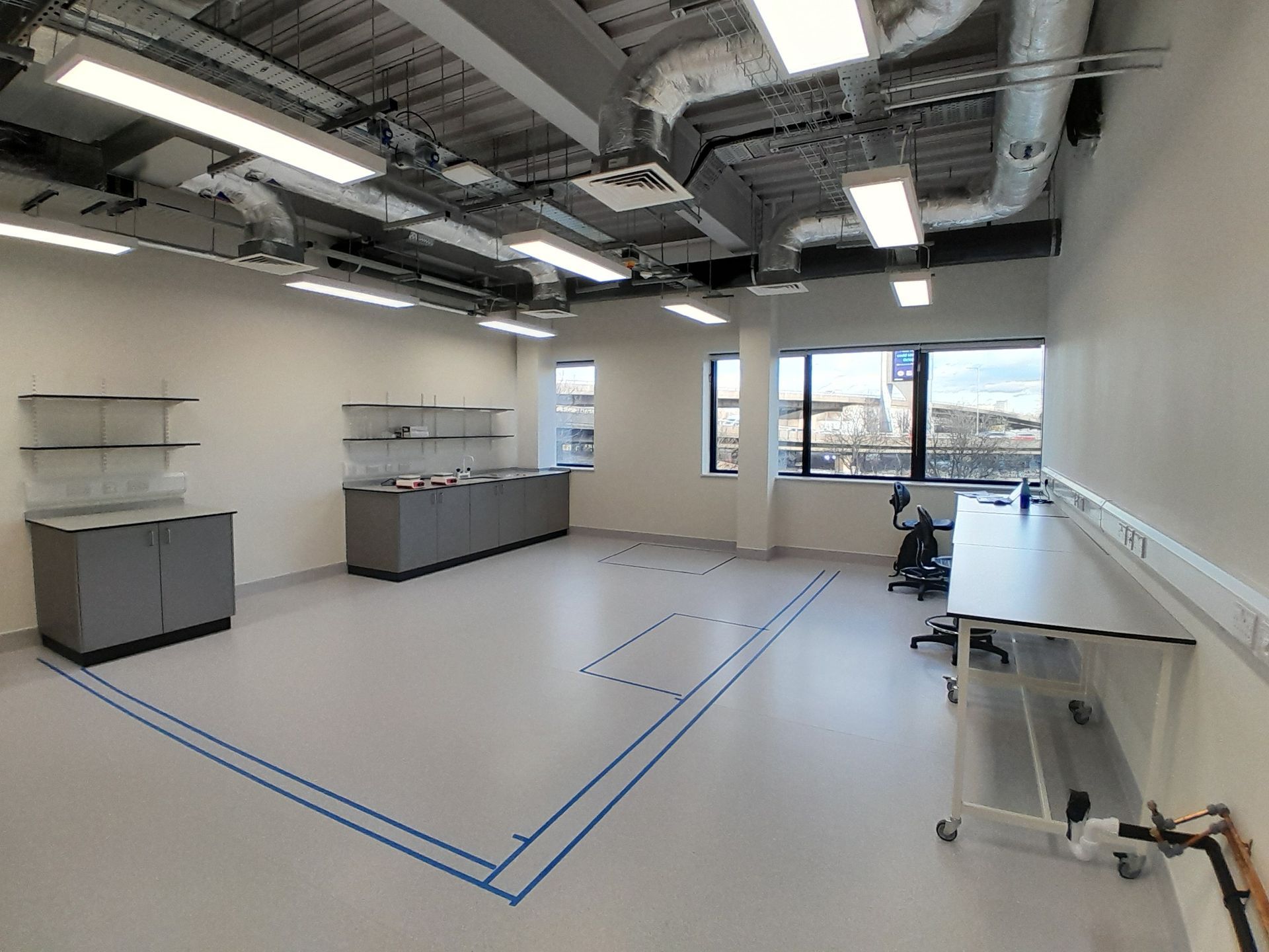 A large empty room with a blue tape on the floor.