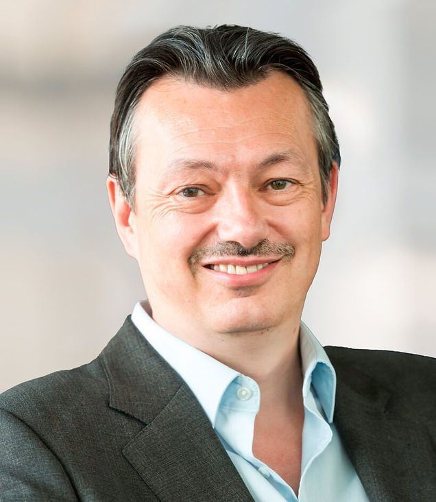 A man in a suit and blue shirt smiles for the camera