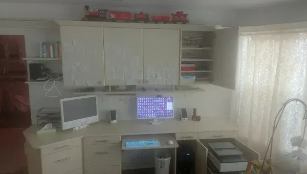 There is a computer on the desk in the middle of the room.