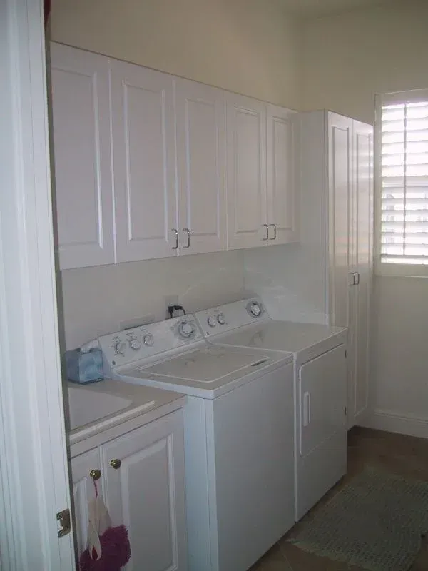 A laundry room with a washer and dryer and white cabinets.