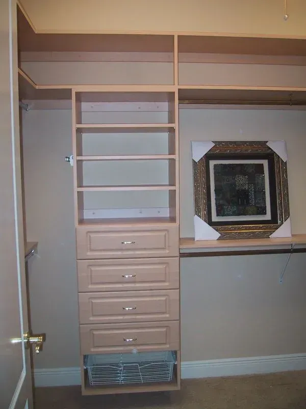 A walk in closet with shelves drawers and a picture on the wall