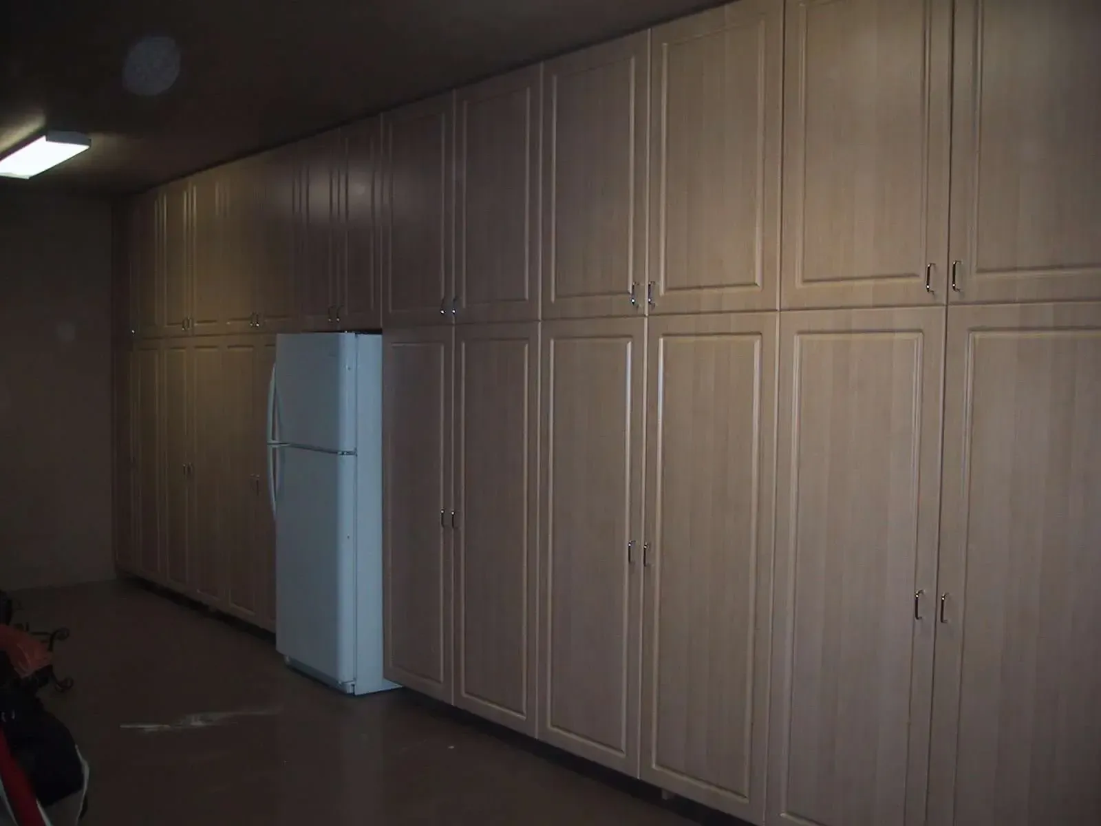 There is a refrigerator in the middle of a room with lots of cabinets.