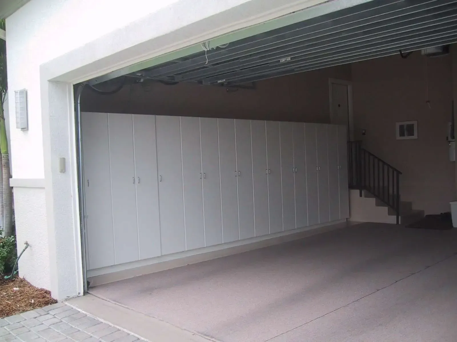 A garage with white cabinets and a staircase in the background.