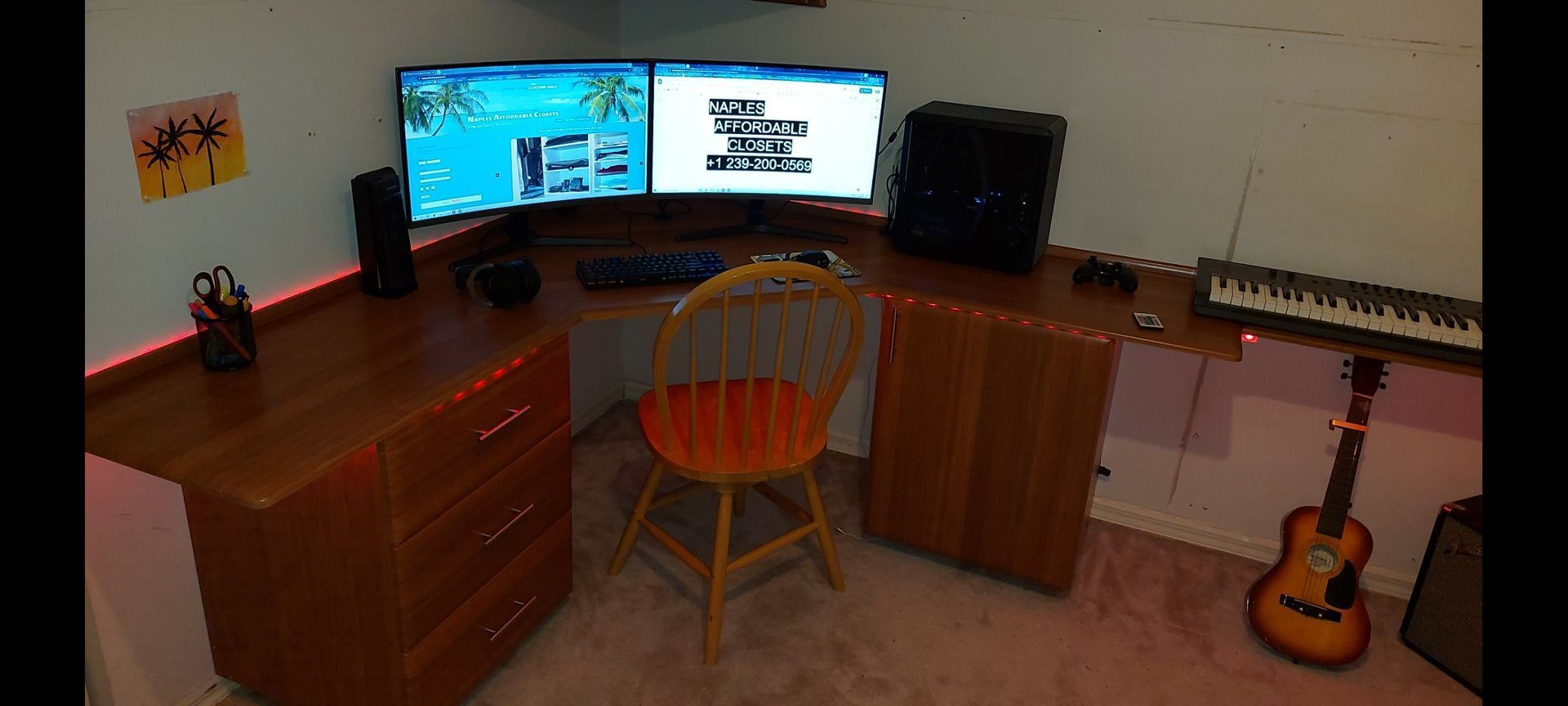A computer desk with two monitors , a keyboard , and a guitar.
