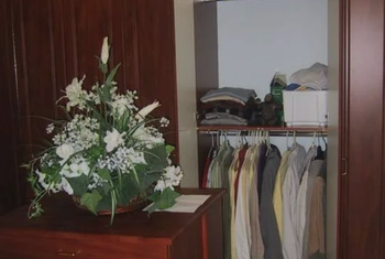 A closet filled with clothes and a vase of flowers on a table.