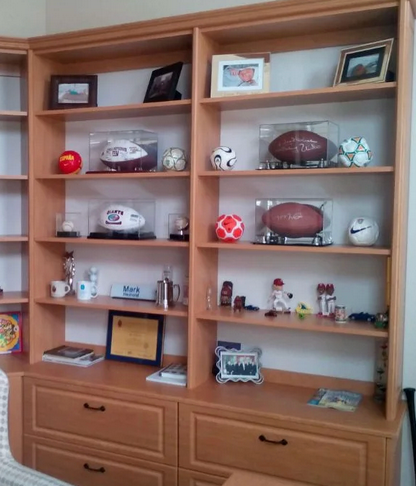 A shelf filled with footballs and other sports memorabilia