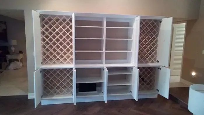 A large white cabinet with wine racks and shelves in a living room.