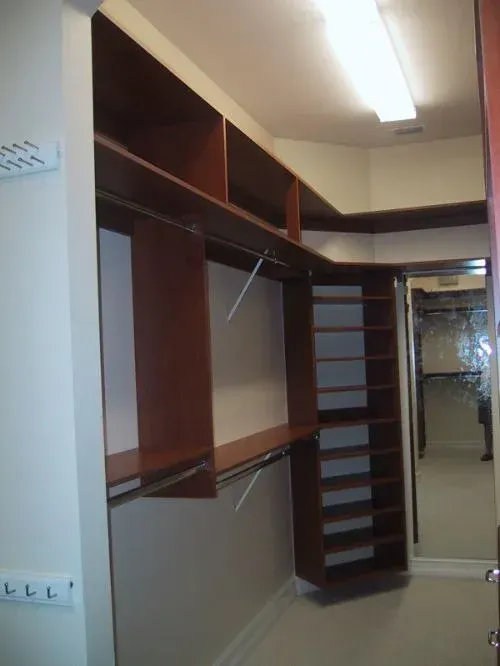 A walk in closet with lots of shelves and a mirror