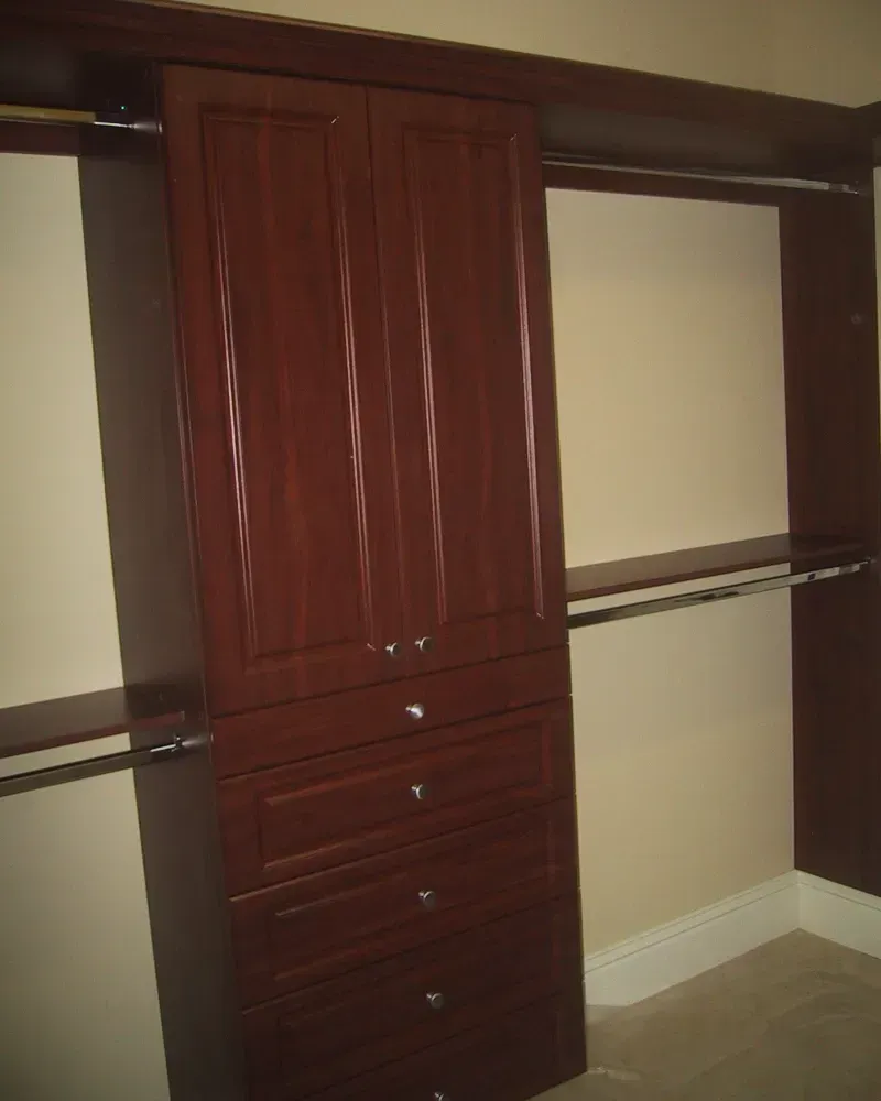 A walk in closet with wooden cabinets and drawers