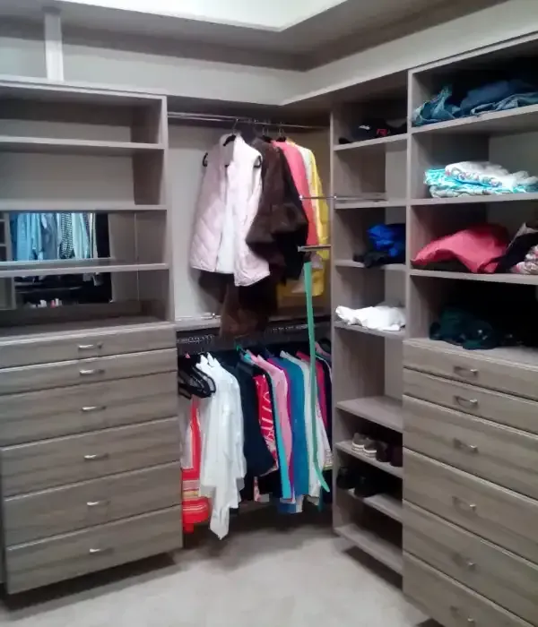A walk in closet with lots of clothes on shelves