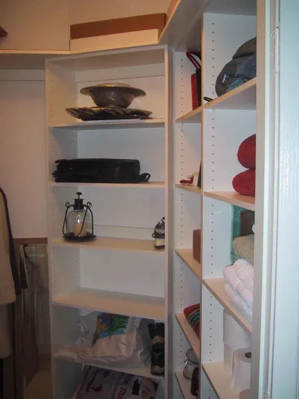 A closet with lots of shelves and a lantern on one of them