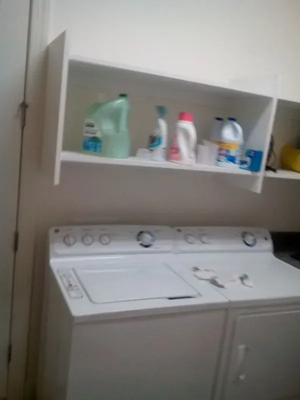 A laundry room with a washer and dryer and shelves