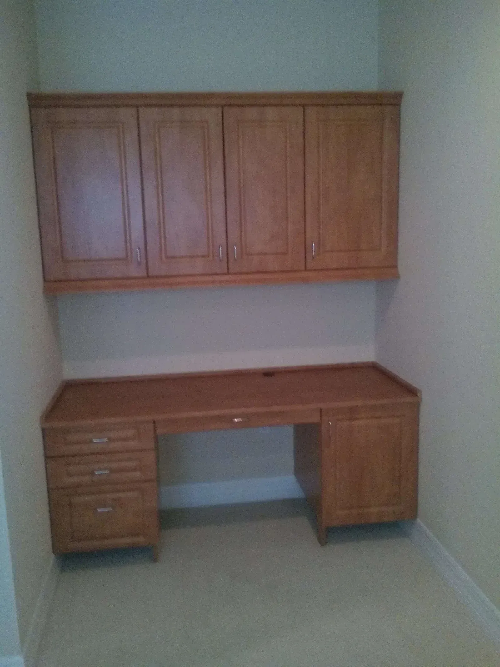 An empty room with a wooden desk and cabinets