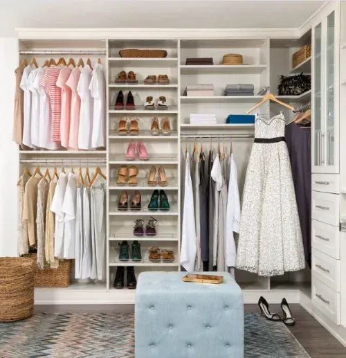 A closet filled with clothes and shoes with a dress hanging in the middle