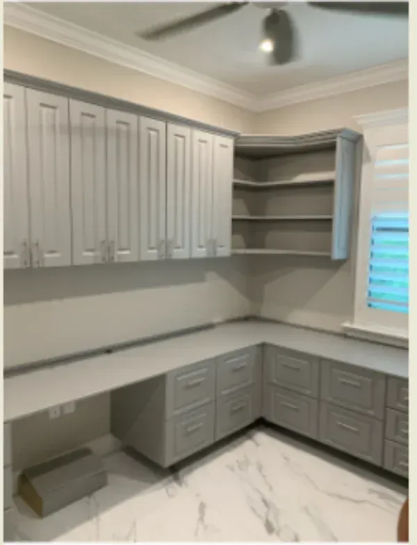 A kitchen with white cabinets and drawers and a window