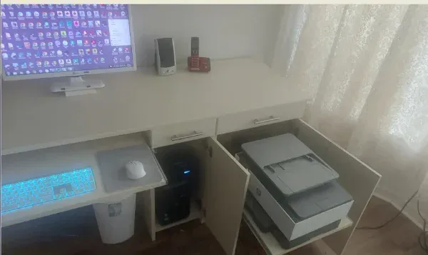 A computer is sitting on a desk next to a printer.