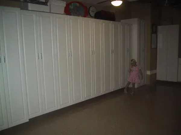 A little girl in a pink dress is standing in a garage.