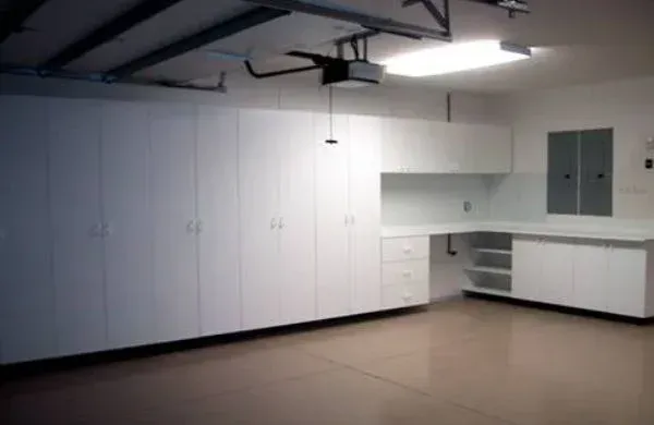 A garage with lots of white cabinets and drawers