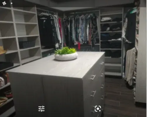 A walk in closet with a large island in the middle.