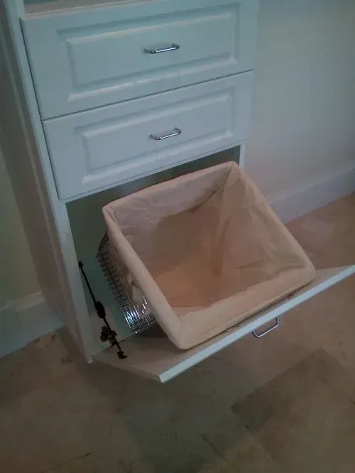A laundry basket is pulled out of a drawer.