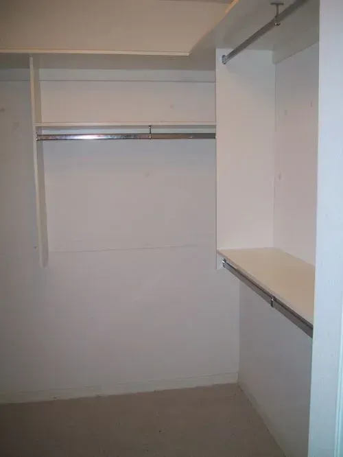 An empty walk in closet with a shelf and clothes racks.