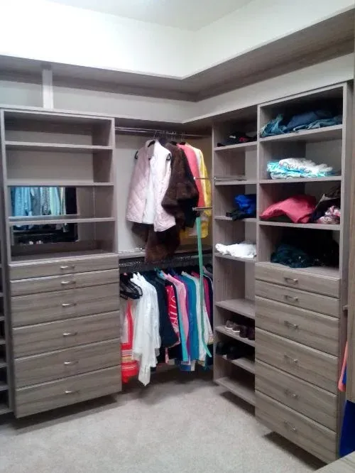 A walk in closet with lots of shelves and drawers