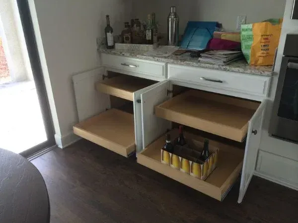 A kitchen with pull out drawers and a bottle of beer
