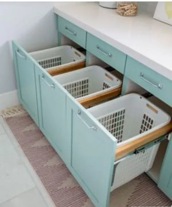 Three laundry baskets are pulled out of a drawer in a laundry room.