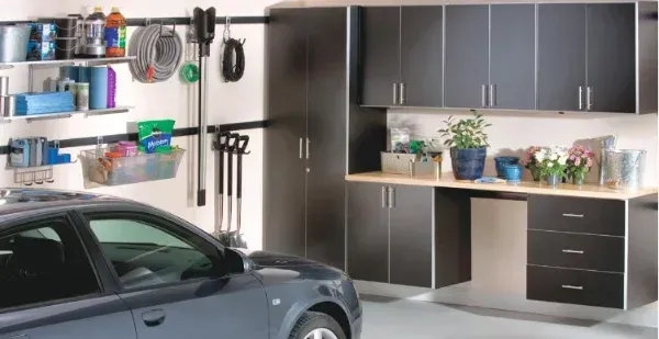 A car is parked in a garage with black cabinets.