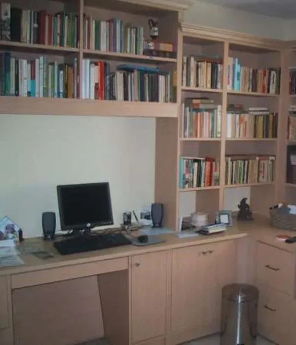 A desk with a computer and bookshelves behind it