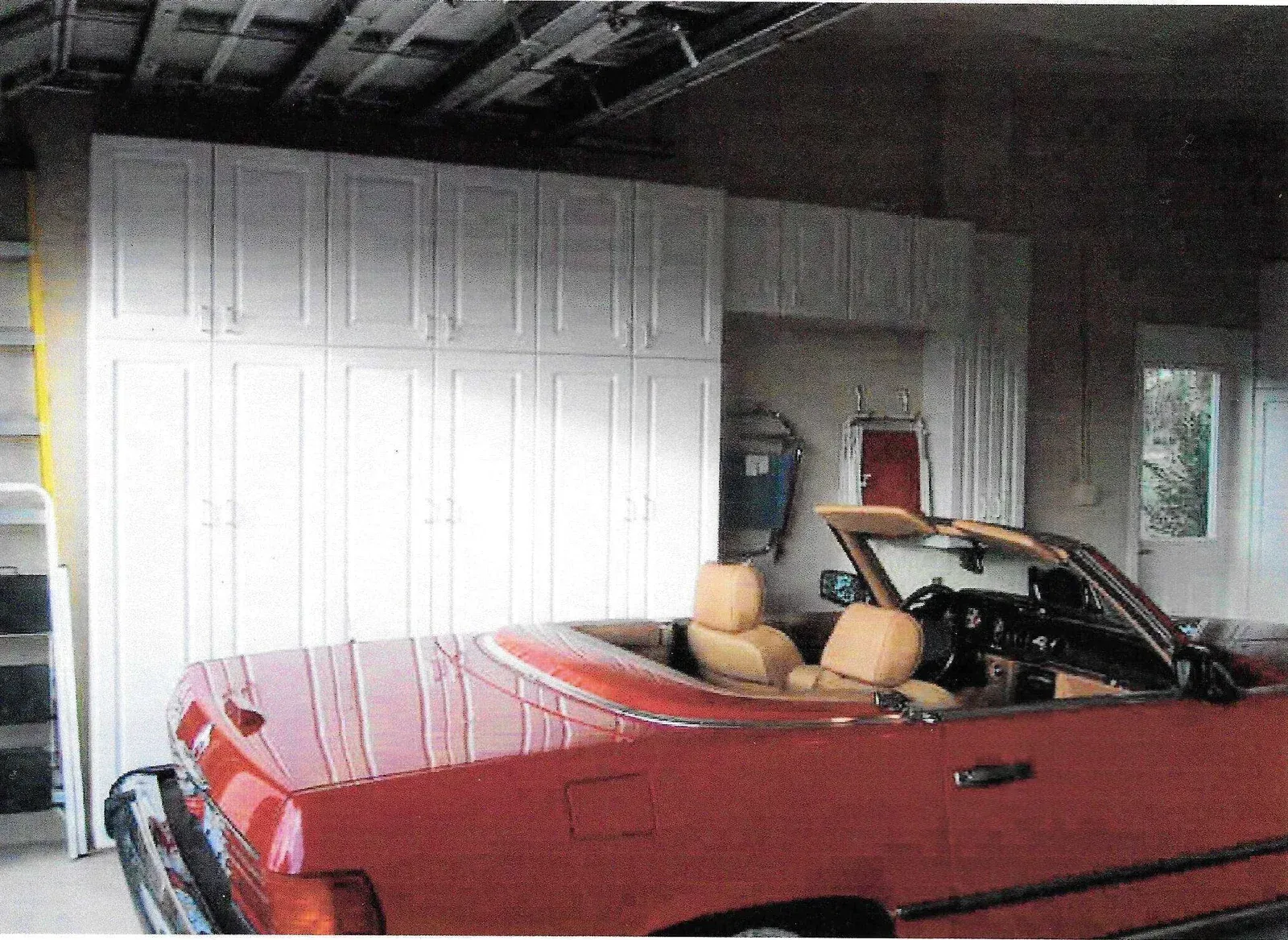 A red convertible car is parked in a garage