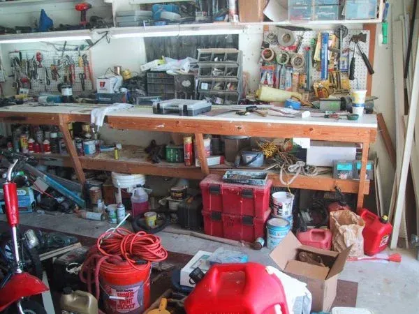 A messy garage with a red jerry can in the middle