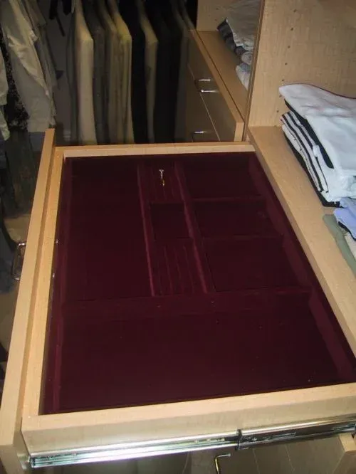 A drawer in a closet has a red velvet tray in it