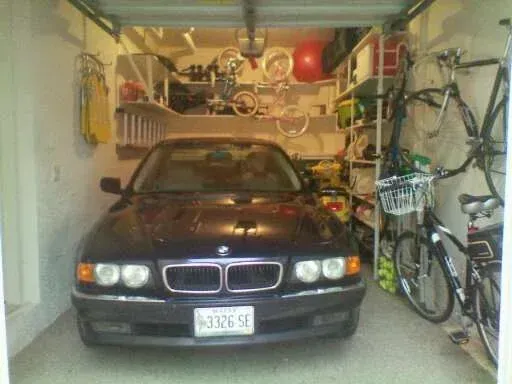 A bmw is parked in a garage with bikes