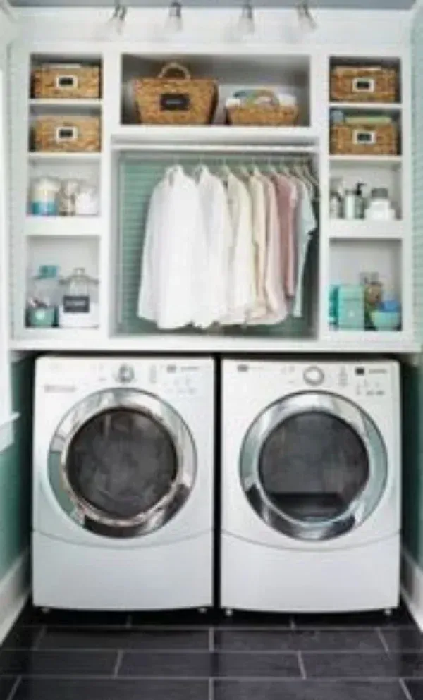 A laundry room with a washer and dryer and clothes hanging on shelves.