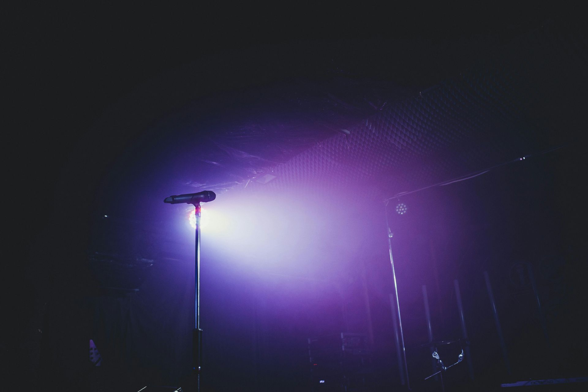Purple stage lights glowing through fog at night, with two lampposts silhouetted in the foreground