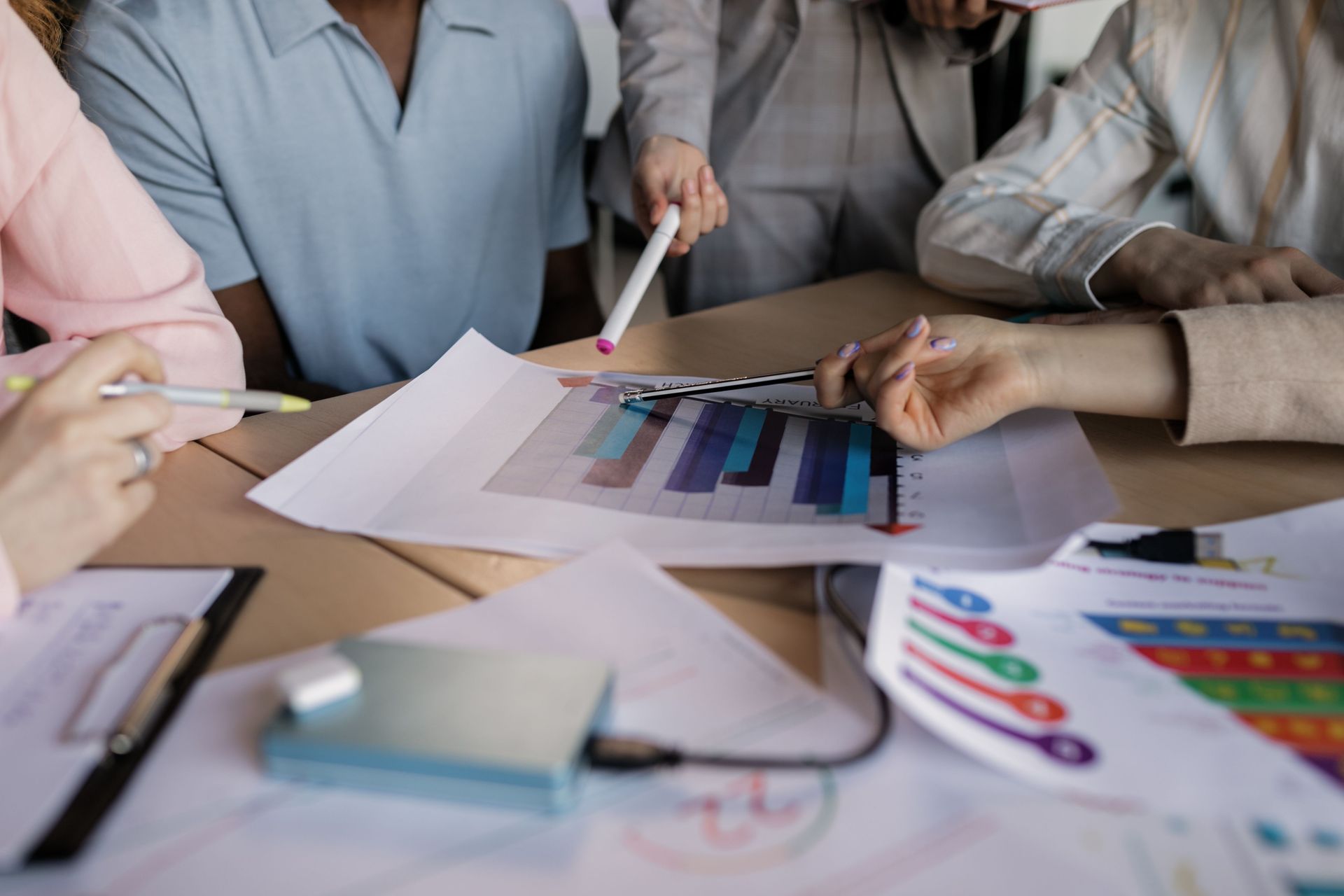 People reviewing color charts and printed designs at a desk with pens and papers