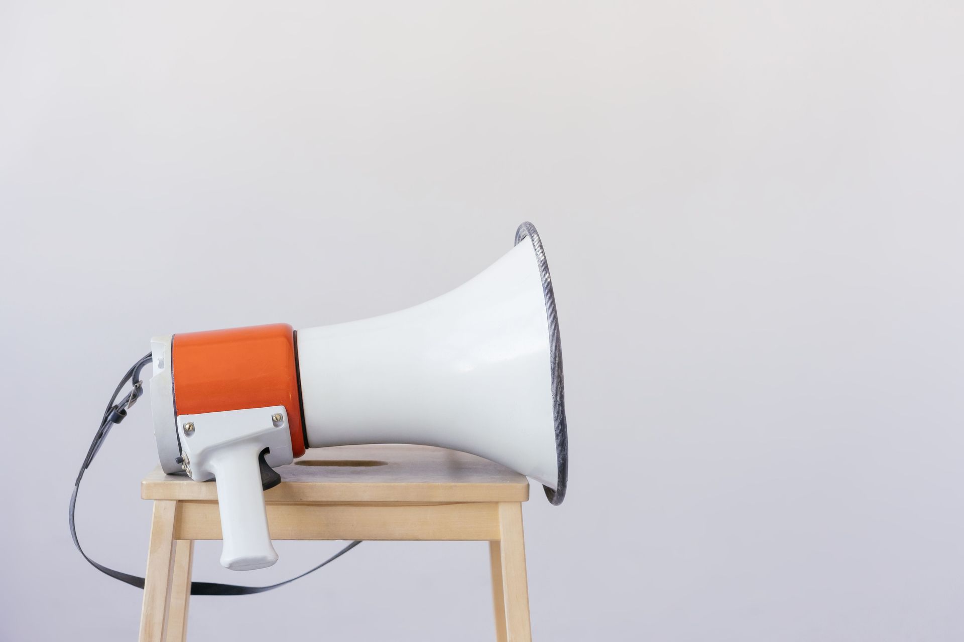 White and orange megaphone resting on a wooden stool against a plain wall
