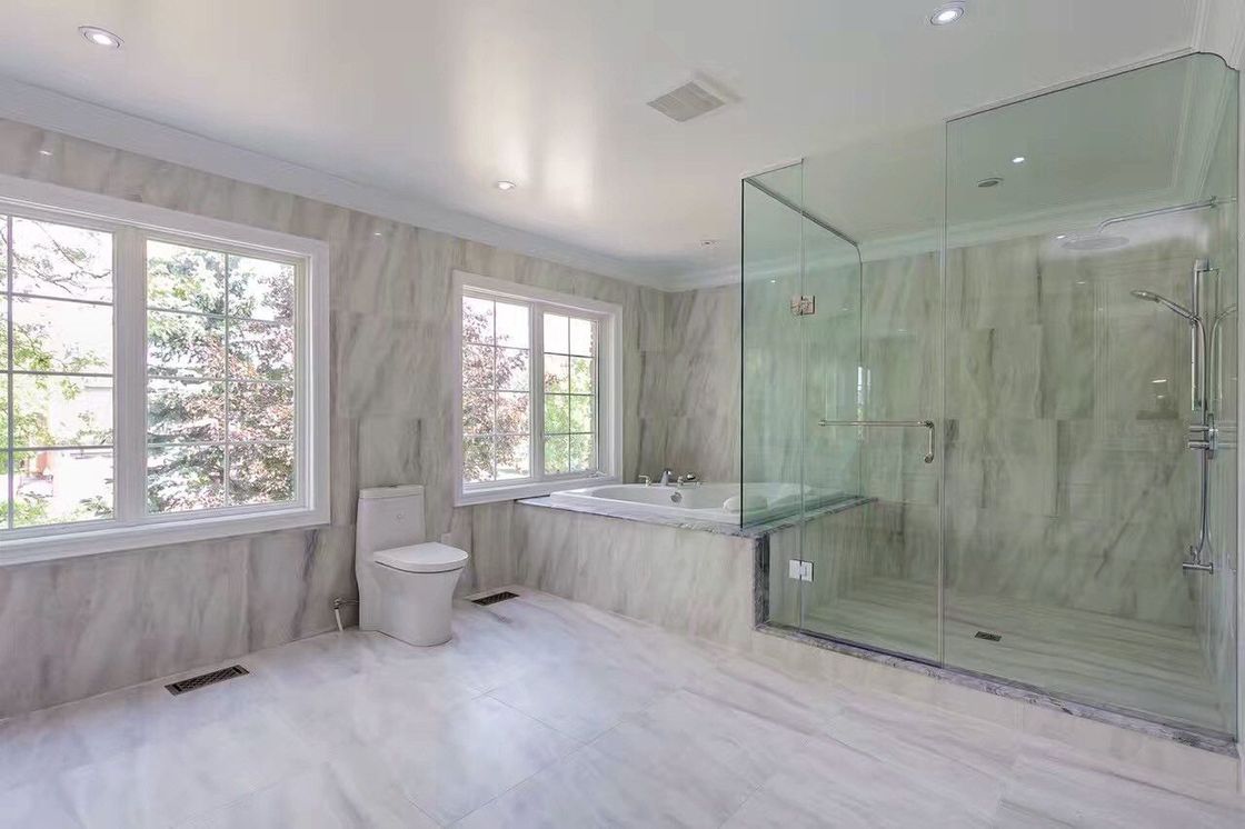 A bathroom with a walk in shower , tub , toilet and window.