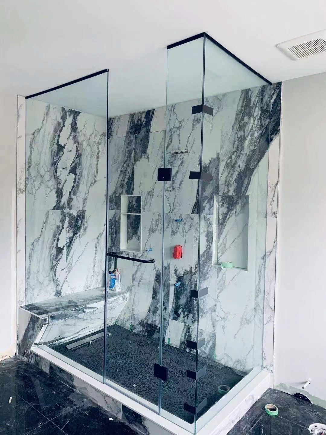 A bathroom with a walk in shower and marble walls.