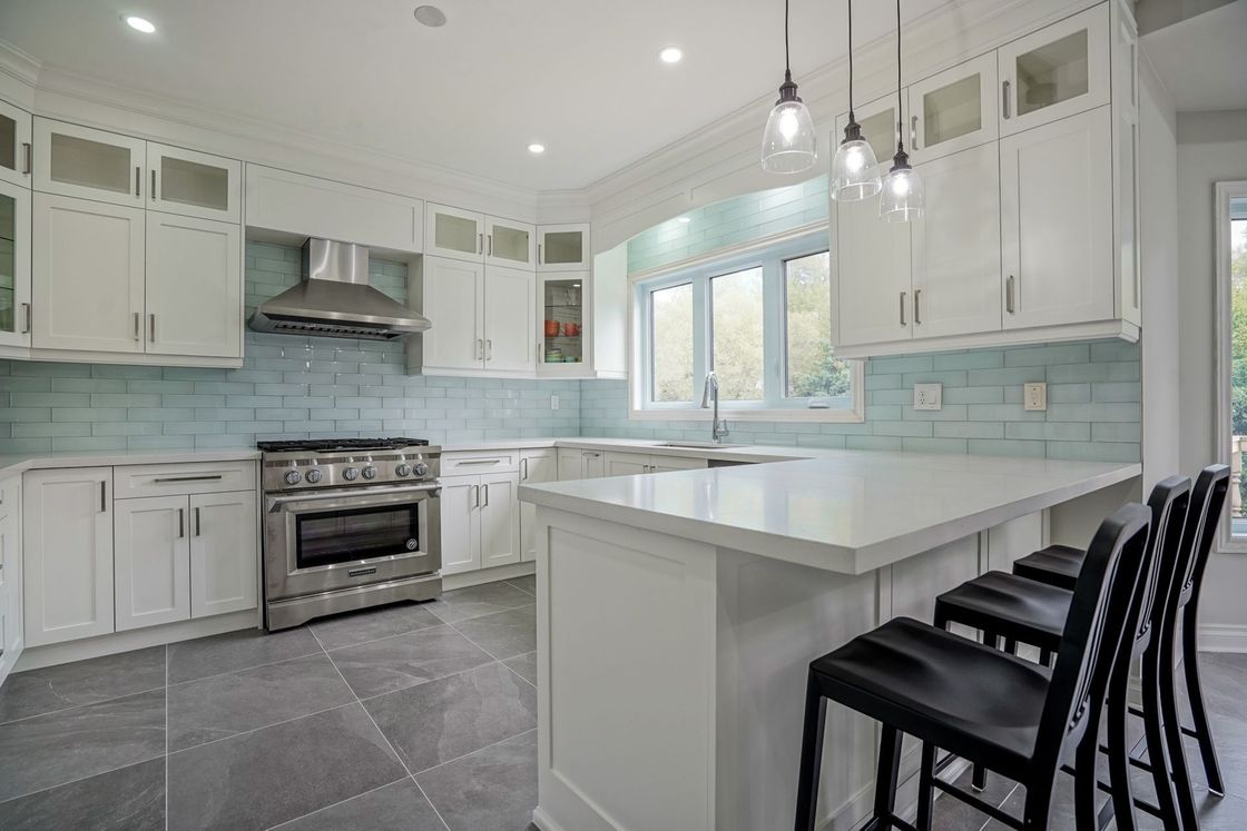 A kitchen with white cabinets , stainless steel appliances , and a large island.