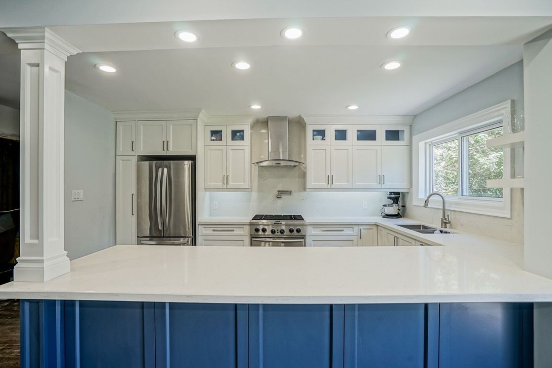 A kitchen with blue cabinets and white counter tops.