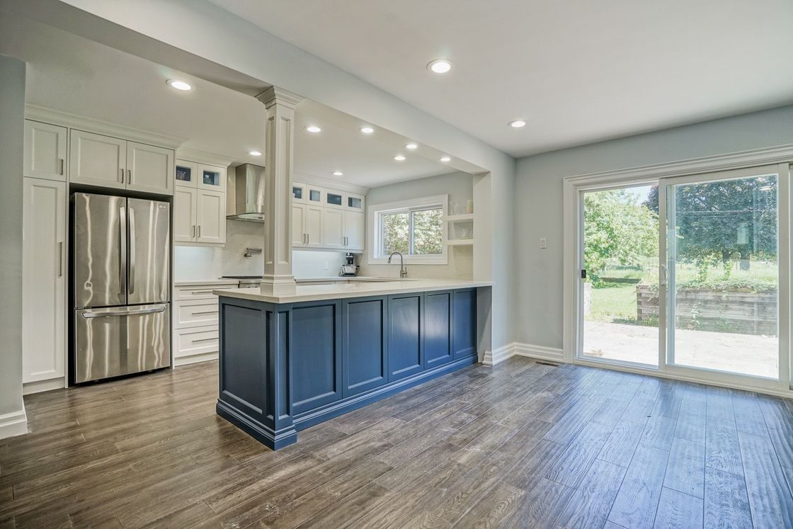 A kitchen with blue cabinets , stainless steel appliances , and hardwood floors.