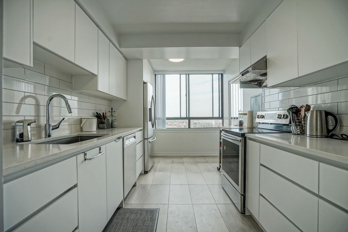 A kitchen with white cabinets , stainless steel appliances , and a large window.
