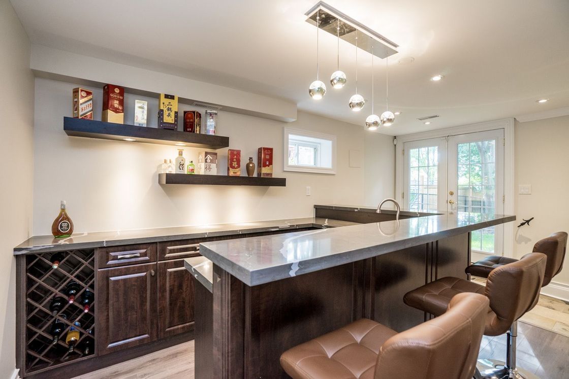A kitchen with a bar and stools and a wine rack.