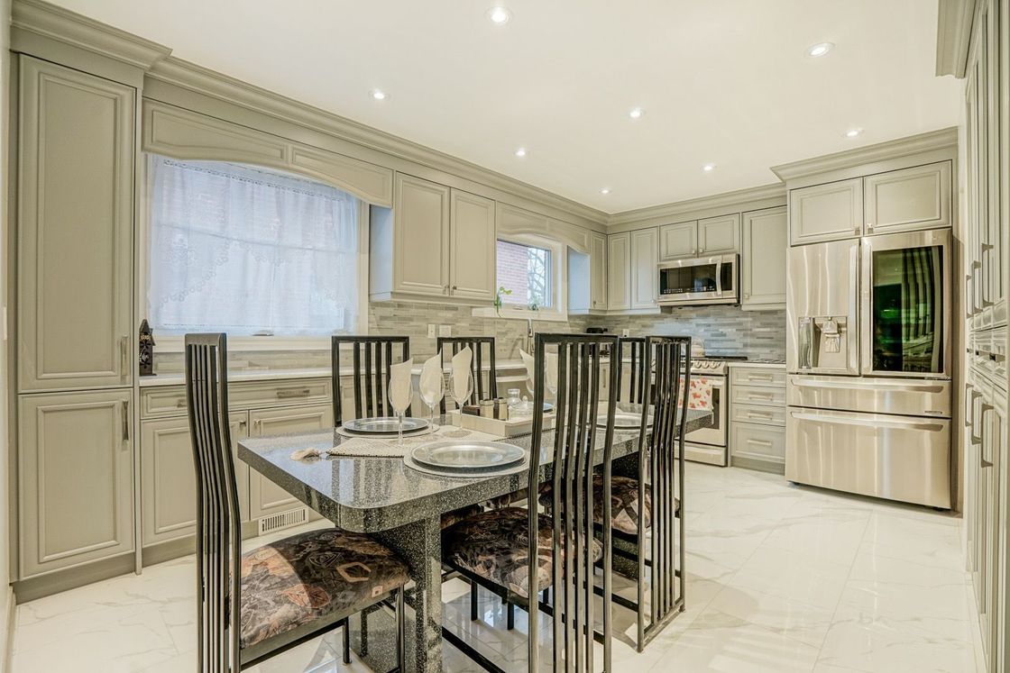 A kitchen with a dining table and chairs and stainless steel appliances.