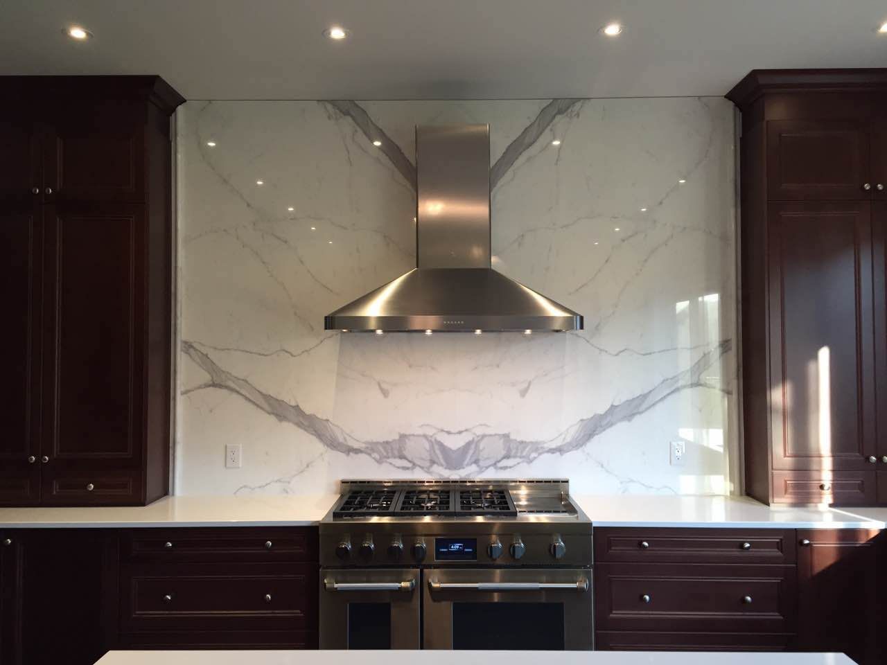 A kitchen with stainless steel appliances and a marble wall