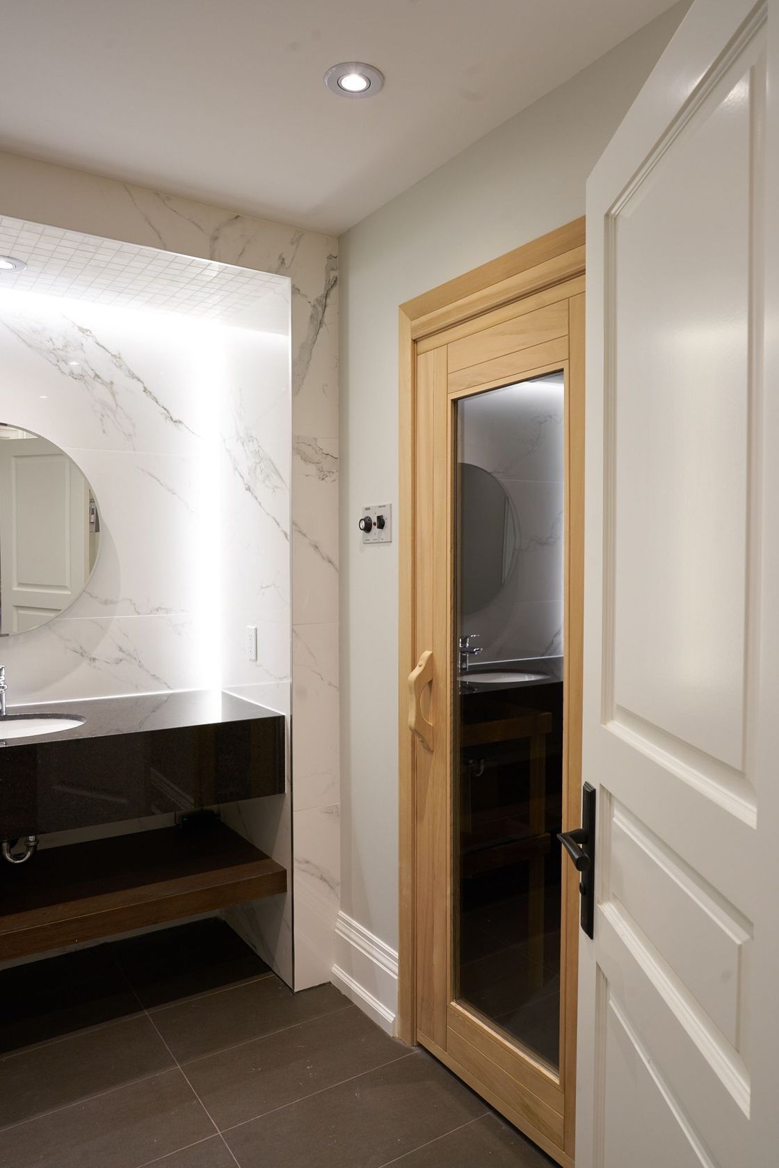 A bathroom with a sink , mirror and door.
