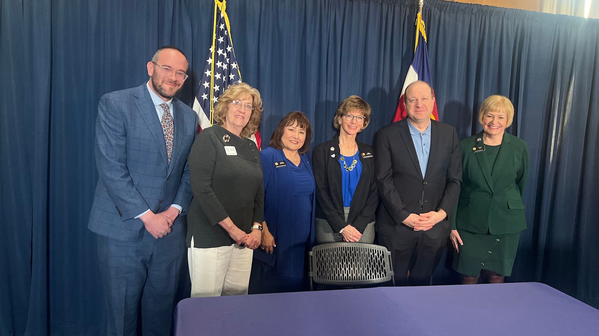 Group of people at a podium with flags. They are likely posing for a photo.