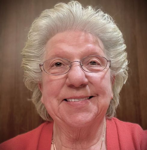 Woman with glasses smiles; blonde hair, red top.